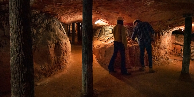 visitors wearing yellow hard hats explore underground mining exhibit