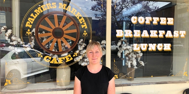 Tenneille Palmer wears a black short-sleeved top and stands in front of Palmers Market Cafe